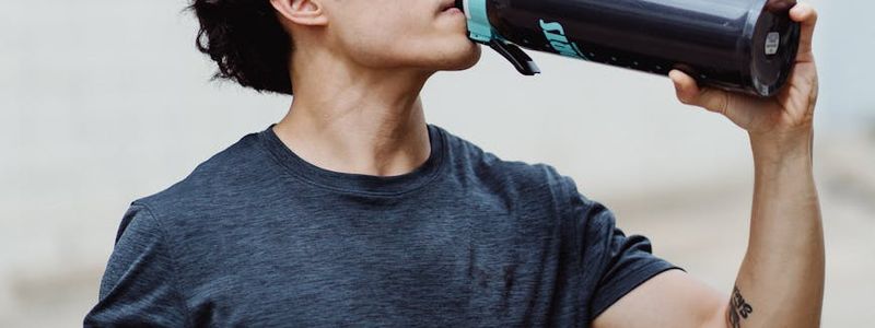 Person hands holding a water bottle after a workout.